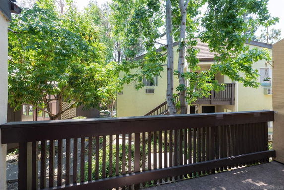 View of apartment buildings surrounded by trees from a wooden deck.