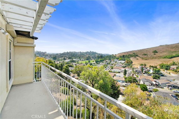 Balcony view overlooking a neighborhood and hills.