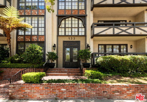 Front view of a multi-story building with balconies and an arched entrance.