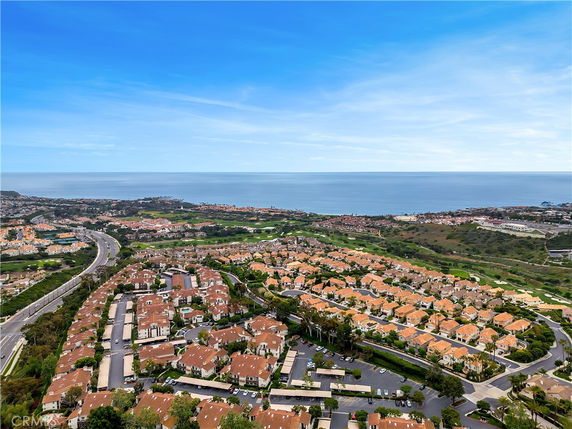 Panoramic view of a residential area with houses and a distant ocean horizon.