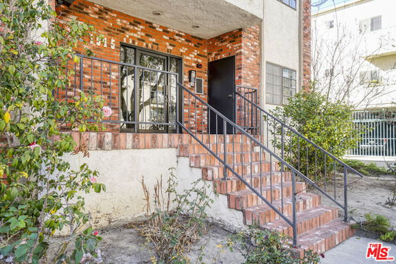 Front view of a building entrance with brick steps and railing.
