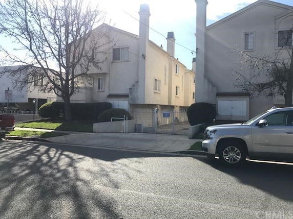 Front view of a multi-story residential building with chimneys and garage doors.
