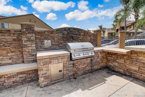 Outdoor barbecue area with a built-in grill and stone wall enclosure.