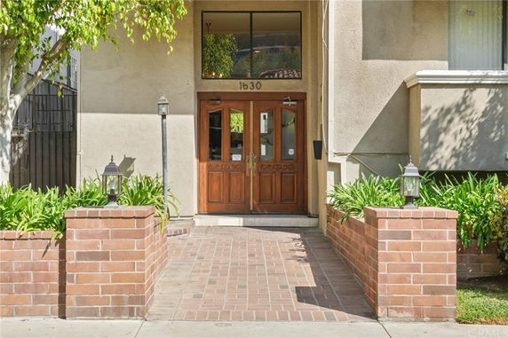 Front view of a building entrance with brick pathway and wooden doors.
