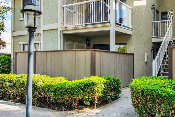 Front view of a building with two balconies and a fenced patio area.