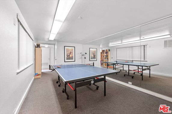 Room with a ping pong table and mirrored wall.