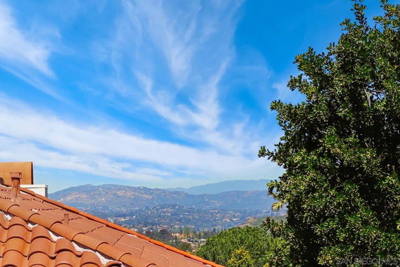 Panoramic view from a rooftop showing distant hills and blue sky.