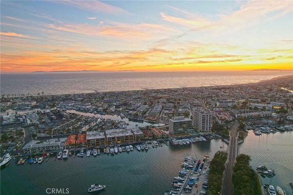 Panoramic view of coastal area with marina and buildings at sunset.