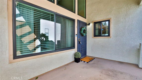 Front view of a house entrance with a metal door and large windows.