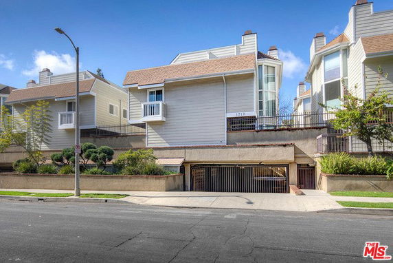 Front view of a multi-story building with sloped roofs and garage entrance.