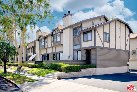 Front view of a multi-story townhouse with a gable roof and chimneys.