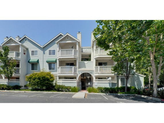 Front view of a multi-story residential building with balconies and an archway entrance.