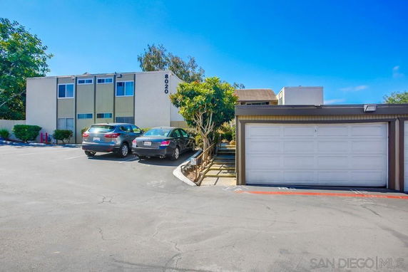 Parking area in front of a two-story building with numbered spaces and a garage.