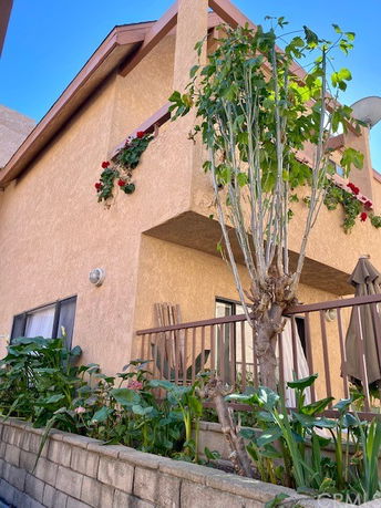 Front view of a two-story house with a balcony and plants.