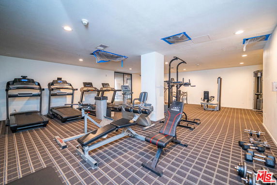 Interior view of a gym with exercise equipment, including treadmills and weight machines.