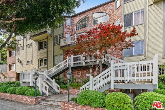 Front view of a multi-story building with brick and siding exterior and a prominent staircase entrance.