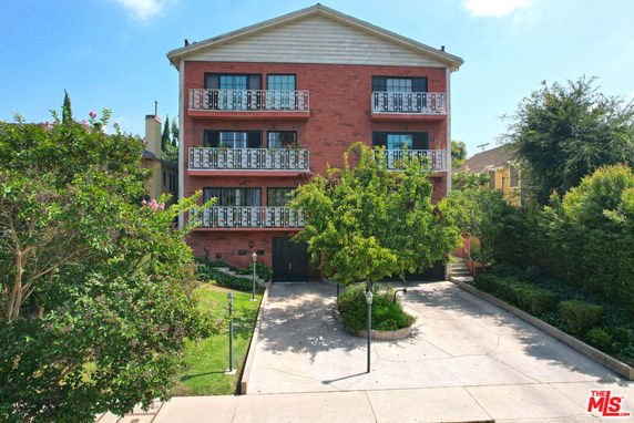 Front view of a multi-story brick building with balconies and a driveway.
