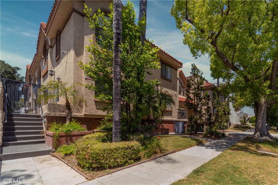 Front view of a multi-story residential building with a staircase leading to the entrance.