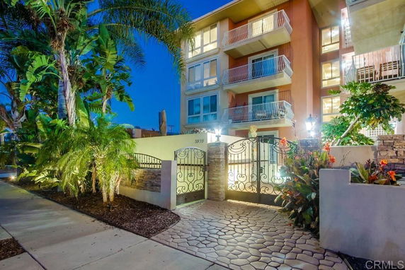 Front view of a multi-story residential building with balconies and gated entrance.