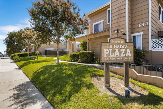 Front view of a condominium building with signage displaying 'La Habra Plaza Condominiums'.