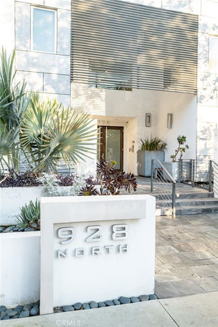 Front view of a modern building with a stylish entrance and decorative plants.