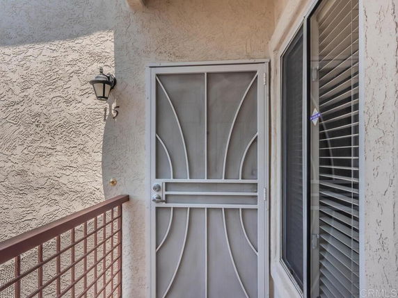 View of a building entrance with a decorative metal door and window.