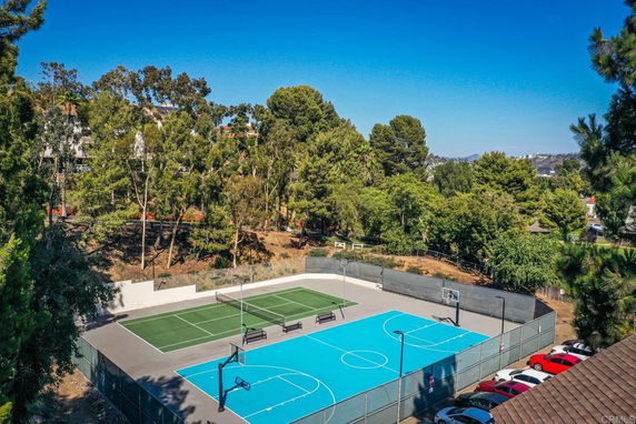 View of outdoor basketball and tennis courts surrounded by trees.