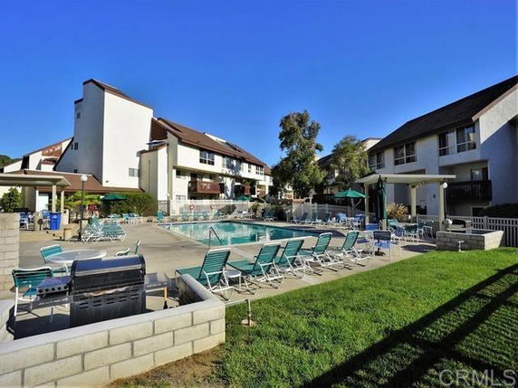 Outdoor swimming pool area surrounded by multi-story residential buildings.