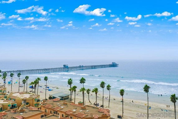 View of a beach and ocean with a pier extending into the water.