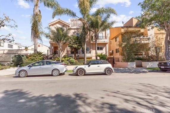 Front view of a multi-story residential building with palm trees.