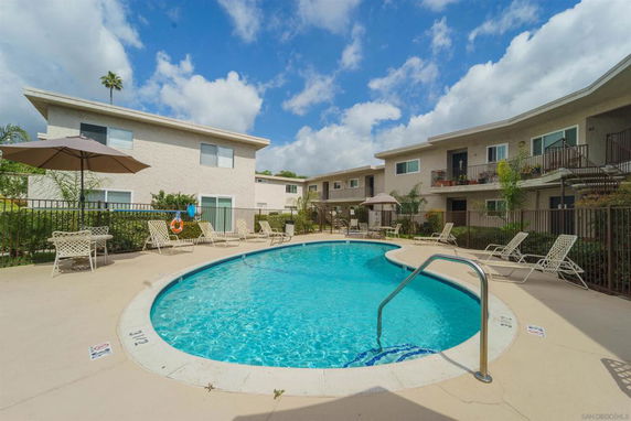 Outdoor swimming pool area with surrounding apartment buildings.