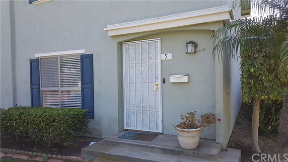 Front view of a house entrance with a metal security door and window shutters.