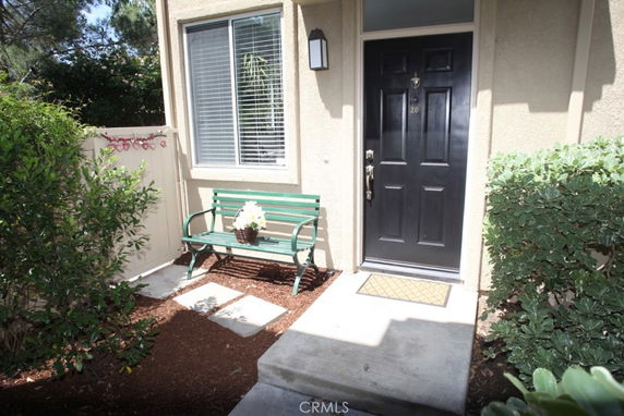 Front view of a house with a dark front door and a nearby bench.