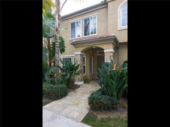 Front view of a two-story house with an arched entrance and tiled roof.