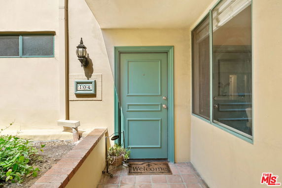 Front view of a house entrance with a teal door and welcome mat
