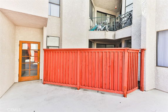 Front view of a building with a red wooden fence and a balcony above.