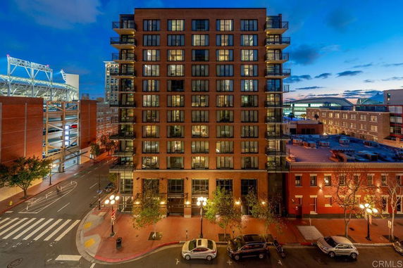 Front view of a multi-story brick building with numerous balconies at night.