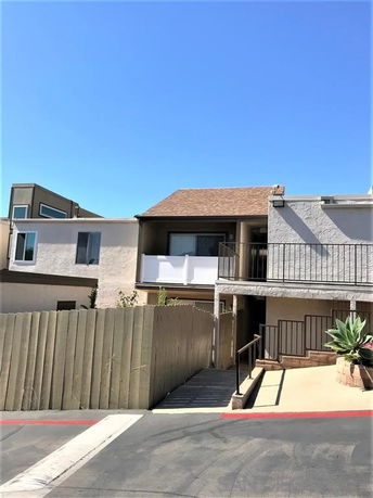 Front view of a two-story house with balconies on both levels and a wooden fence.
