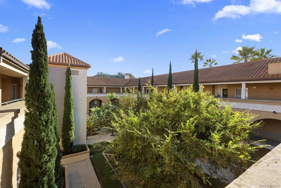 View of a residential building with tiled roofs and trees in the courtyard.
