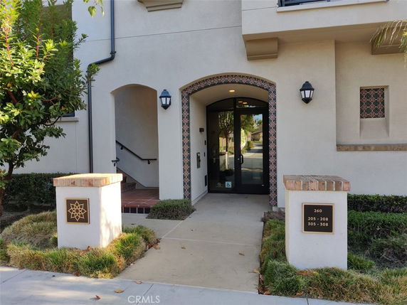 Front view of a building entrance with decorative tiles and light fixtures.