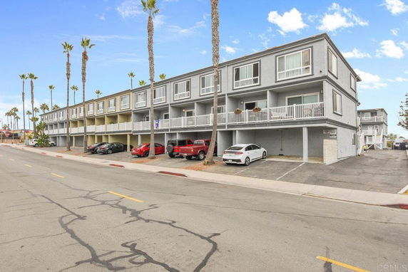 Front view of a multi-story residential building with parking space underneath.