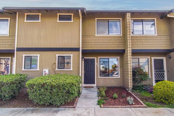 Front view of a two-story townhouse with a black door and multiple windows.
