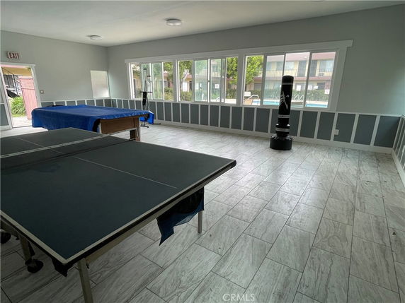 Indoor recreation room with table tennis and exercise equipment.