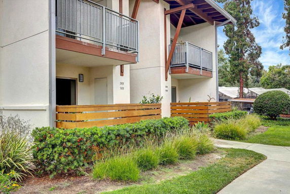 Front view of a multi-story building with balconies and wooden fencing.
