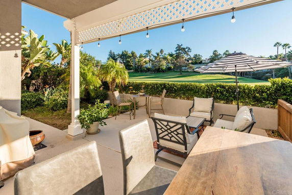Patio with seating area overlooking a green lawn and trees.