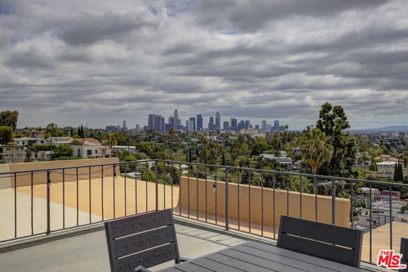 Panoramic city skyline view from a rooftop with seating area.