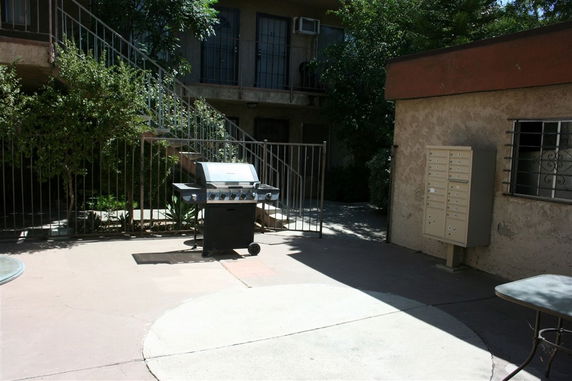 Outdoor area with a barbecue grill and mailbox unit near an apartment building.