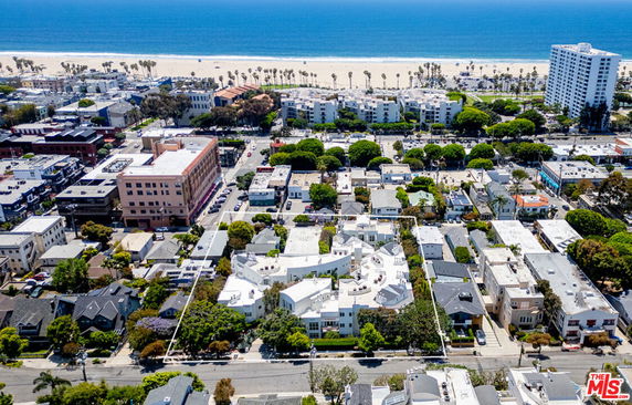 Panoramic view of a coastal neighborhood with a beachfront in the background and various buildings.
