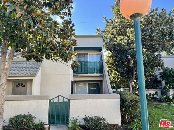 Front view of a two-story residential building with a small balcony and gated entrance.