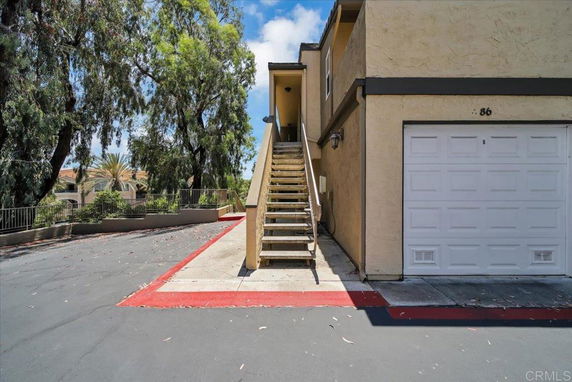 Front view of a building with an external staircase and a garage.